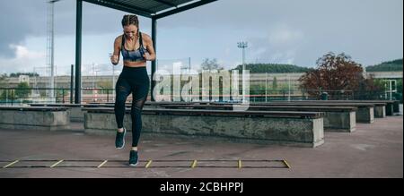 Sportive saltando su una scaletta di agilità Foto Stock