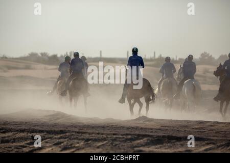 Gruppo di giovani cavalieri che praticano su un terreno desertico foto Foto Stock