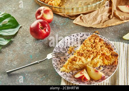 Torte fatte in casa, torta in un piatto da forno e una fetta su un piatto con pesche e pere su cemento grigio-blu. Foto Stock