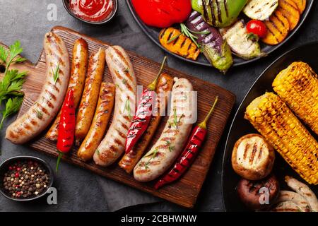 Salsicce alla griglia e verdure con spezie ed erbe. Vista dall'alto in piano Foto Stock