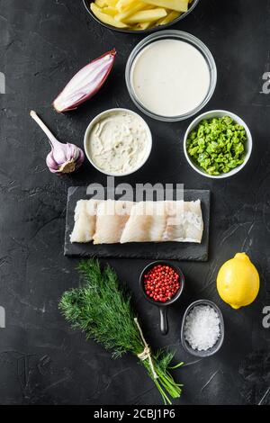 Pesce biologico e patatine ingredienti filetti di merluzzo crudo su pastella di ardesia di pietra, potatoe, salsa tartaro, piselli minati, limone, scalogno, menta, aglio, sale Foto Stock