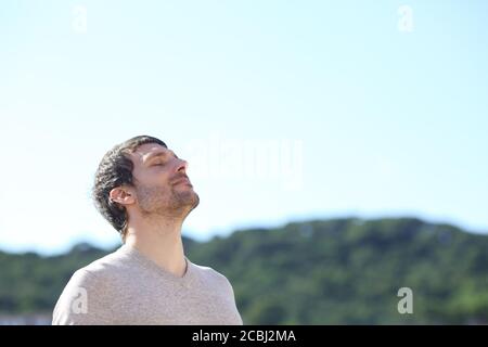 Uomo che respira aria fresca all'aperto in piedi in montagna molla Foto Stock