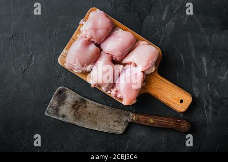 Cosce di pollo crudo con scissione di carne, su sfondo nero, vista dall'alto Foto Stock