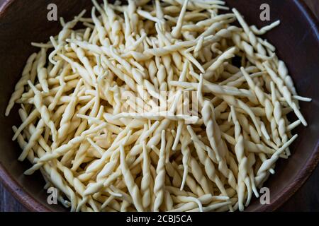 Trofie fresche Pasta italiana cruda in ciotola di legno. Pronto a cucinare. Foto Stock