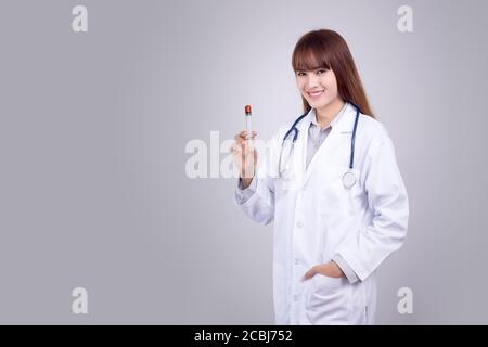 Concetto sano : giovane medico asiatico con siringa ipodermica in mano isolato su sfondo grigio. Medico , clinica , poster ospedaliero e pubblicità Foto Stock