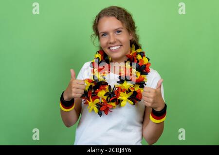 Felice bionda femmina tifosa di calcio dalla Germania isolato sul verde sfondo Foto Stock