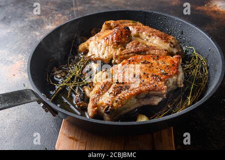 Grigliate di maiale alle ossa con condimenti e grigliate su padella calda con fumo proprio dal fuoco vicino vista laterale. Foto Stock