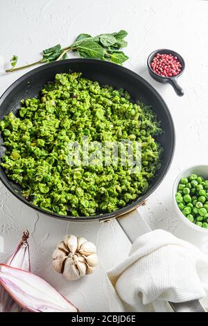 Ricetta di piselli ai funghi padella cotti e piselli in ciotola con pepe di scalogno di menta e sale su una superficie di pietra bianca vista laterale del keto food biologico Foto Stock