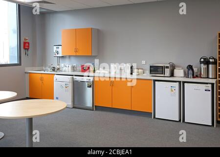 Camera del personale in una scuola secondaria di Londra appena completata. Presenta un'area cucina con frigoriferi e lavastoviglie e un'area salotto in primo piano. Foto Stock