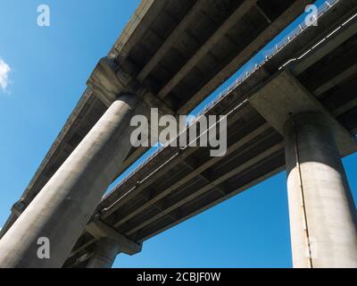 Ponte dell'autostrada a più corsie con colonne in cemento armato, vista dal basso. Sfondo blu cielo Foto Stock