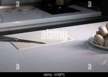 taglio di cartone bianco di plastica con funghi champignon su di esso. cottura processo. Foto di alta qualità Foto Stock