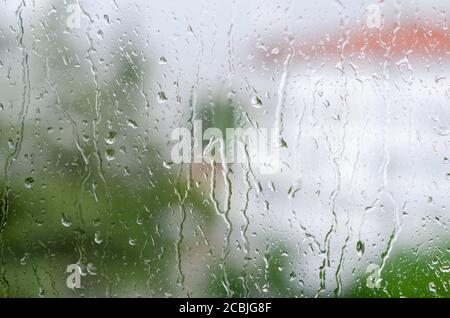 Gocce di pioggia che colpiscono il vetro della finestra Foto Stock