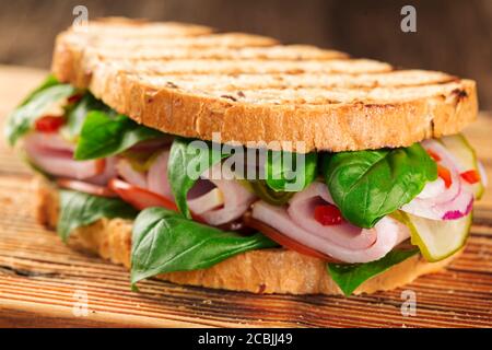 Poster delizioso sandwich prosciutto primo piano su tavola di legno cucina, vista dall'alto Foto Stock