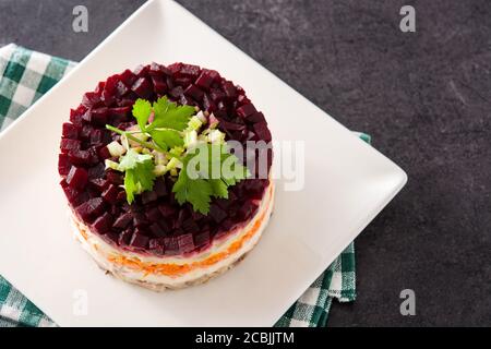 Insalata tradizionale russa di aringhe con barbabietole e carote su nero sfondo ardesia Foto Stock