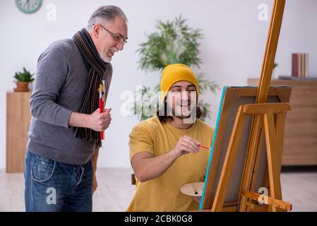 Giovane uomo che prende lezione da pittore esperto Foto Stock