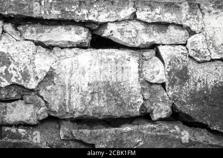 Vecchio muro di pietra imbiancato. La parete di pietra è fratturata e deve essere riparata Foto Stock