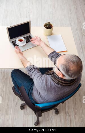 Dipendente maschile senior che lavora da casa durante la pandemia Foto Stock