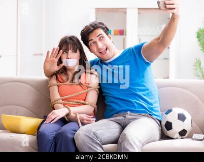L'uomo la legatura fino a sua moglie di guardare lo sport calcio Foto Stock