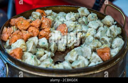 'Shumi' (Shaomai) o Kanom Jeeb' un 'Dim Sum' Cinese tradizionale gnocchi al vapore con gamberi e maiale all'interno in metallo vassoio in vendita in strada Foto Stock