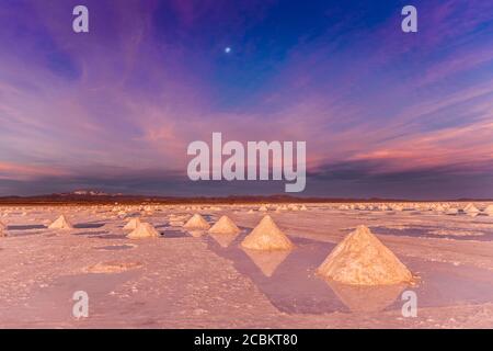 Le pile di sale si raccolgono sulle saline al tramonto, Salar de Uyuni, Antipano meridionale, Bolivia, Sud America Foto Stock