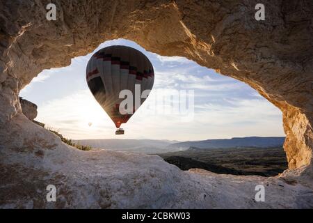 Mongolfiera incorniciata tra la formazione rocciosa all'alba, Goreme National Park, Cappadocia, Anatolia, Turchia Foto Stock