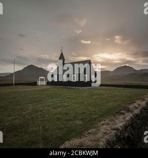 Budarkirkja chiesa e catena montuosa, raggi del sole attraverso le nuvole, Budir, Penisola di Snaefellsnes, Islanda Foto Stock