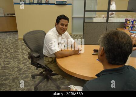 Austin, TX 1 agosto 2006: Un rappresentante del servizio clienti ispanico aiuta un cliente ad aprire un conto durante il grande evento di apertura di una banca centrale bancaria Capital One in un'area suburbana in rapida crescita. ©Bob Daemmrich Foto Stock