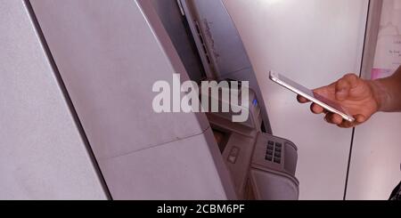 DISTRETTO KATNI, INDIA - 20 SETTEMBRE 2019: Uomo mano che tiene mobile vicino alla macchina ATM per il controllo del messaggio di prelievo di contanti. Foto Stock