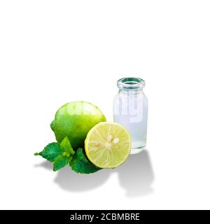 Limoni verdi e succo di limone in un vaso isolato con sfondo bianco Foto Stock