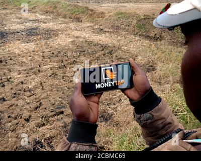 DISTRETTO KATNI, INDIA - 20 DICEMBRE 2019: Soldi Tap Instant Loan logo presentato sullo schermo digitale del telefono intelligente da parte della gente del villaggio indiano mano che tiene m Foto Stock