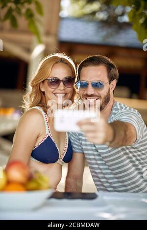 Sorridente famiglia rilassante al picnic in Nature.Couple godere insieme all'aperto e fare selfie. Foto Stock