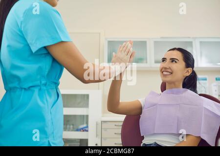 Felice dentista e paziente donna dare cinque con la mano in clinica dentale. Foto Stock