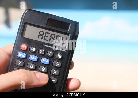 Parola pronta sul display della calcolatrice vicino alla spiaggia estiva. Concetto di lavoro a distanza Foto Stock