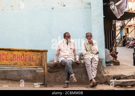 Bhopal, Madhya Pradesh, India - Marzo 2019: Due anziani indiani seduti su una panchina di pietra su una strada nella città vecchia di Bhopal. Foto Stock