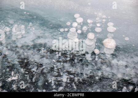 Bolle di gaz di metano congelate in ghiaccio limpido sul lago Baikal, Russia Foto Stock