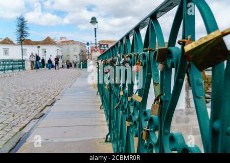 Tavira, Portogallo - 24 marzo 2018: Serrature d'amore appese sulla ringhiera del ponte. Le coppie amorevoli attaccano i lucchetti come simbolo dell'amore eterno. Foto Stock
