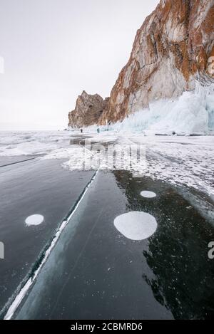 Crepe di ghiaccio e bolle di metano sulla superficie congelata del lago Baikal, Russia Foto Stock