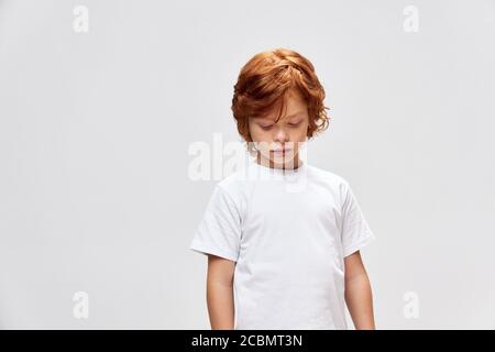 teen rosso guardando giù t-shirt bianca studio vista ritagliata Foto Stock