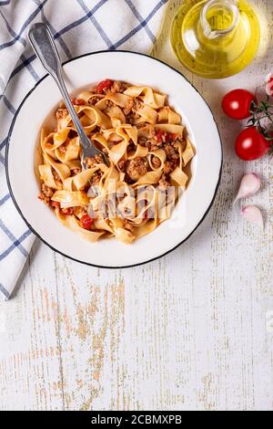 Tradizionale bolognese di pasta italiana su un piatto bianco su fondo di legno, vista dall'alto. Foto Stock