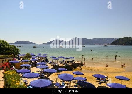 Vista panoramica sul Golfo dei Poeti da una spiaggia di sabbia con ombrelloni e persone che nuotano e prendisole in estate, Lerici, la Spezia, Liguria, Italia Foto Stock