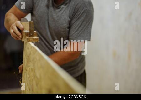 Uomo che macina la clapboard. Uomo che lavora con legno. Riparazione domestica. Texture Foto Stock