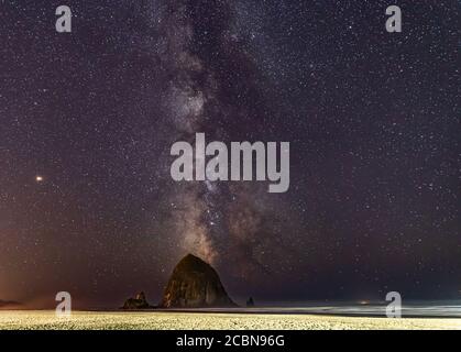 Milky Way nel cielo sopra Haystack Rock su Cannon Spiaggia in Oregon Foto Stock