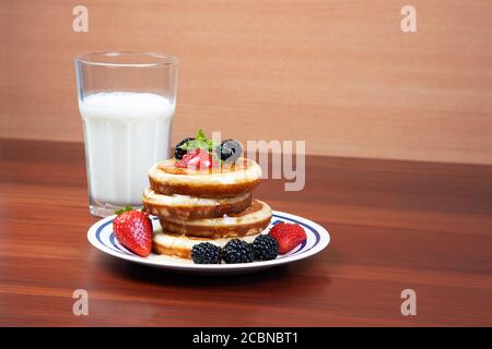 frittelle al miele, fragole, more e bicchiere di latte Foto Stock