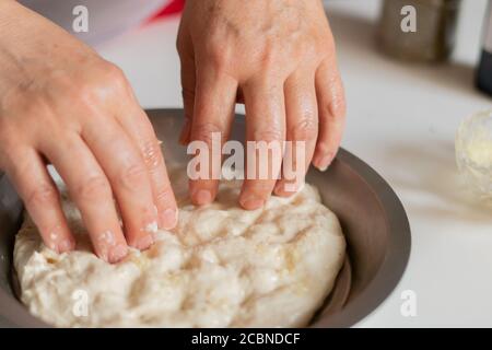 Le mani della ragazza preparano l'impasto in cucina da vicino Foto Stock