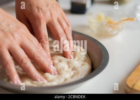 Le mani della ragazza preparano l'impasto in cucina da vicino Foto Stock