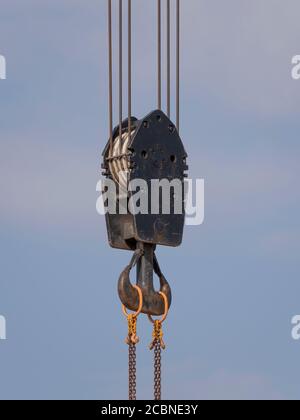 Il gancio della gru con strisce rosse e bianche pensili, cielo blu in background. Foto Stock