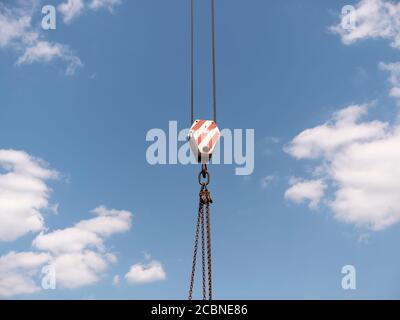 Il gancio della gru con strisce rosse e bianche pensili, cielo blu in background. Foto Stock