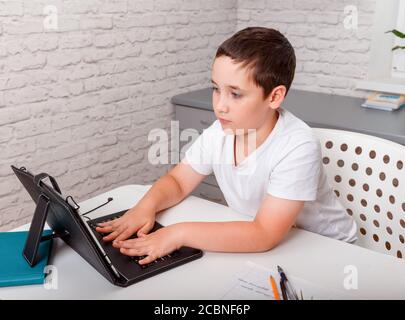 Boy usa un tablet digitale per videochiamare con il suo insegnante. Homeschooling Foto Stock