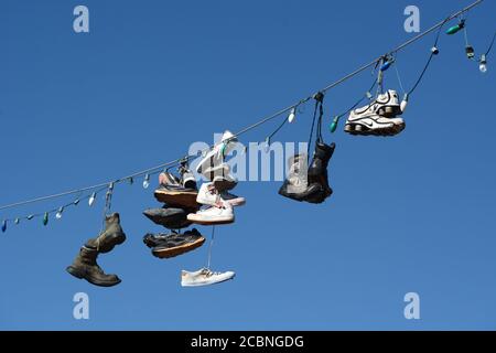 Le coppie di scarpe e scarponi pendono da un filo elettrico che corre su una strada nella zona rurale di Madrid, New Mexico USA Foto Stock