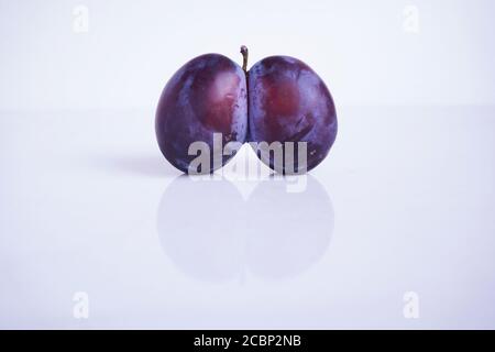 Primo piano brutto prugna. Prugna viziata a forma di cuore su sfondo bianco. Frutta brutta. Cibo divertente. Cibo viziato. Concetto di cibo brutto alla moda Foto Stock